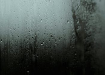 Atmospheric close-up of raindrops on a window, capturing a serene and moody scene.