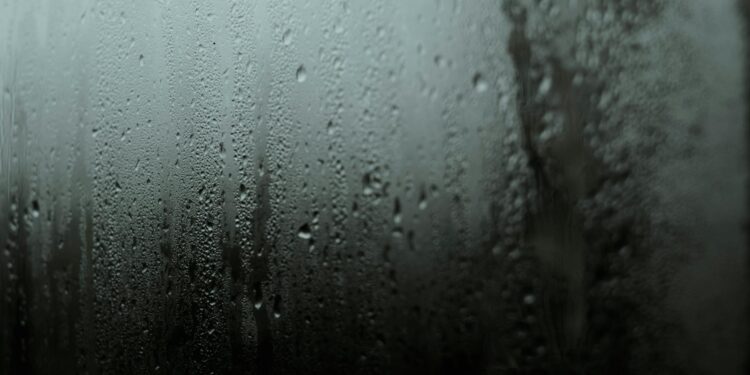 Atmospheric close-up of raindrops on a window, capturing a serene and moody scene.