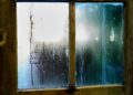 Close-up of a moist wooden window pane with condensation creating artistic streaks in Leiden, Netherlands.