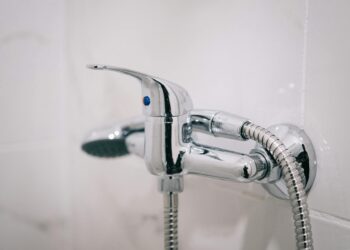A detailed view of a sleek chrome shower faucet in a clean bathroom setting.
