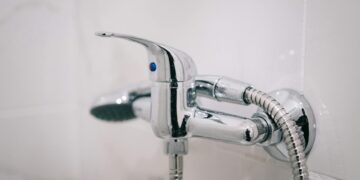 A detailed view of a sleek chrome shower faucet in a clean bathroom setting.