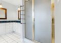 Elegant bathroom featuring a shower with gold trim and marble countertops, highlighting modern interior design.