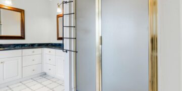 Elegant bathroom featuring a shower with gold trim and marble countertops, highlighting modern interior design.