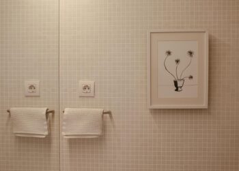 Elegant bathroom with framed art and textured towels on tiled wall.