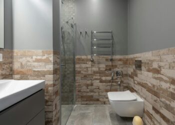 Stylish contemporary bathroom featuring a glass shower and brick accent wall.
