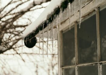 Close-up of icicles hanging from a snow-covered rooftop, emphasizing winter's chill.