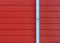 A minimalist photo of a red wall with a white rain gutter, showing clean lines and vibrant color contrast.