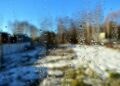 A window with water droplets overlooking a snowy winter landscape under a clear blue sky.