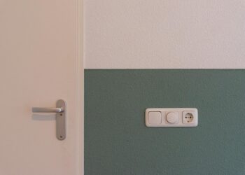 Modern interior scene showing a door handle and a power outlet on a two-toned wall.