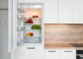 Contemporary kitchen with refrigerator filled with fresh bright tomatoes lettuce and bell peppers