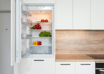 Contemporary kitchen with refrigerator filled with fresh bright tomatoes lettuce and bell peppers