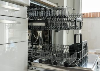 Open and empty dishwasher in a sunlit modern kitchen ready for use.