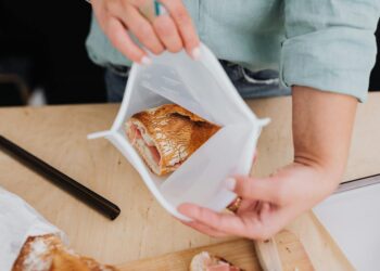 Person storing bread in a reusable silicone bag, promoting zero waste lifestyle.