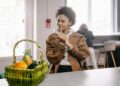 African American woman smiling with a fruit basket indoors, conveying a warm lifestyle moment.