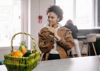 African American woman smiling with a fruit basket indoors, conveying a warm lifestyle moment.