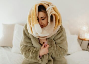 Woman wrapped in a fluffy blanket enjoying a cozy moment at home.