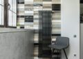Stylish home interior featuring a tiled wall, radiator, and designer chair.