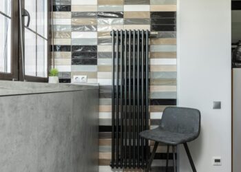 Stylish home interior featuring a tiled wall, radiator, and designer chair.