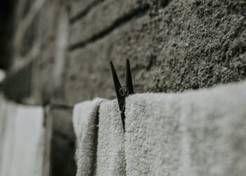 Black and white close-up of towels drying on a wall, featuring a clothespin.