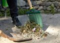 Close-up of a person raking leaves and debris outdoors.