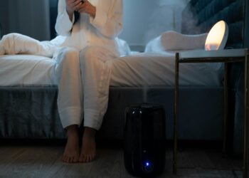 A serene bedroom scene with humidifier mist illuminating soft lighting, creating a calm atmosphere.