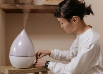 A woman adjusts a humidifier indoors, promoting relaxation and air quality.