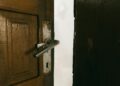 A rustic wooden door slightly ajar with a metal handle, creating a mysterious ambiance.