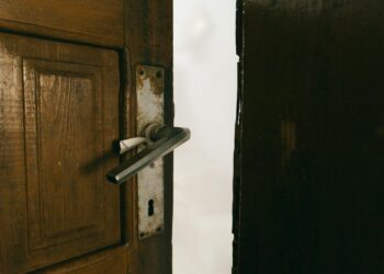 A rustic wooden door slightly ajar with a metal handle, creating a mysterious ambiance.