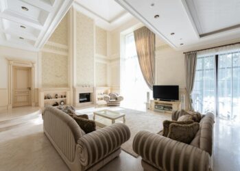 Interior of spacious living room with sofas near table on carpet next to TV and windows with curtains