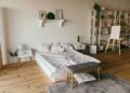 Spacious modern bedroom with minimalist decor, featuring a low bed, wooden floors, and shelf storage.