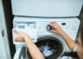 A person in a laundry room adjusting settings on a washing machine.