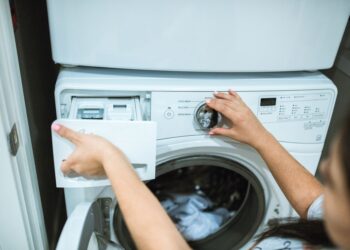 A person in a laundry room adjusting settings on a washing machine.
