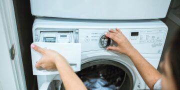 A person in a laundry room adjusting settings on a washing machine.