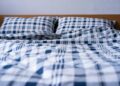 Comfortable double bed with blue plaid pattern bedding in a modern bedroom setting.
