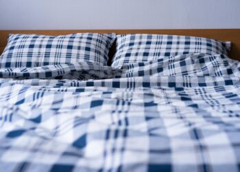 Comfortable double bed with blue plaid pattern bedding in a modern bedroom setting.