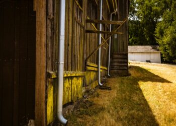 A rustic barn with rain gutters in a sunny rural setting, capturing rustic charm.