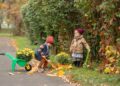 Two children enjoy a playful gardening session in a park filled with autumn colors.