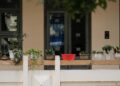 A peaceful balcony featuring a variety of potted plants and a red container, perfect for gardening enthusiasts.