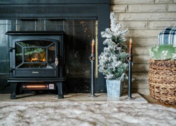 A warm and cozy interior featuring a burning stove, blankets, and a small decorated Christmas tree.