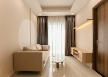 A minimalist living room with a beige sofa, modern table, and soft lighting.
