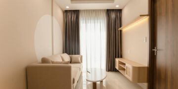 A minimalist living room with a beige sofa, modern table, and soft lighting.