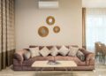 Comfortable sofa with cushions placed near table with magazines in lounge in daytime