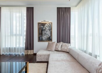 Bright and spacious modern living room featuring a sectional couch, large windows, and chic decor.