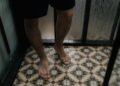 Close-up view of a person standing with wet feet on a tiled shower floor.