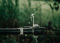 A detailed view of a leaking water pipe in a lush green garden setting.