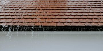 Brown roof tiles with rainwater cascading down, showcasing architectural texture and detail.