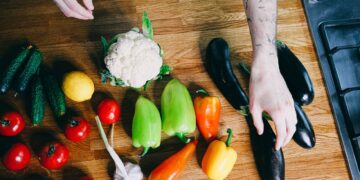 Colorful vegetables including peppers, tomatoes, and eggplants arranged on a kitchen counter.