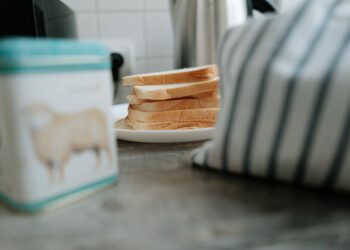 Close-up of sliced bread on a ceramic plate beside a striped cloth. Perfect for cozy kitchen or breakfast themes.