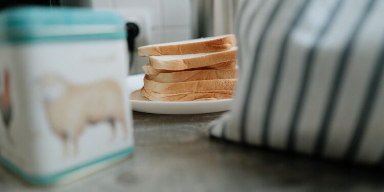 Close-up of sliced bread on a ceramic plate beside a striped cloth. Perfect for cozy kitchen or breakfast themes.