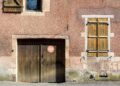 Charming old building facade with rustic wooden doors and shutters in urban setting.